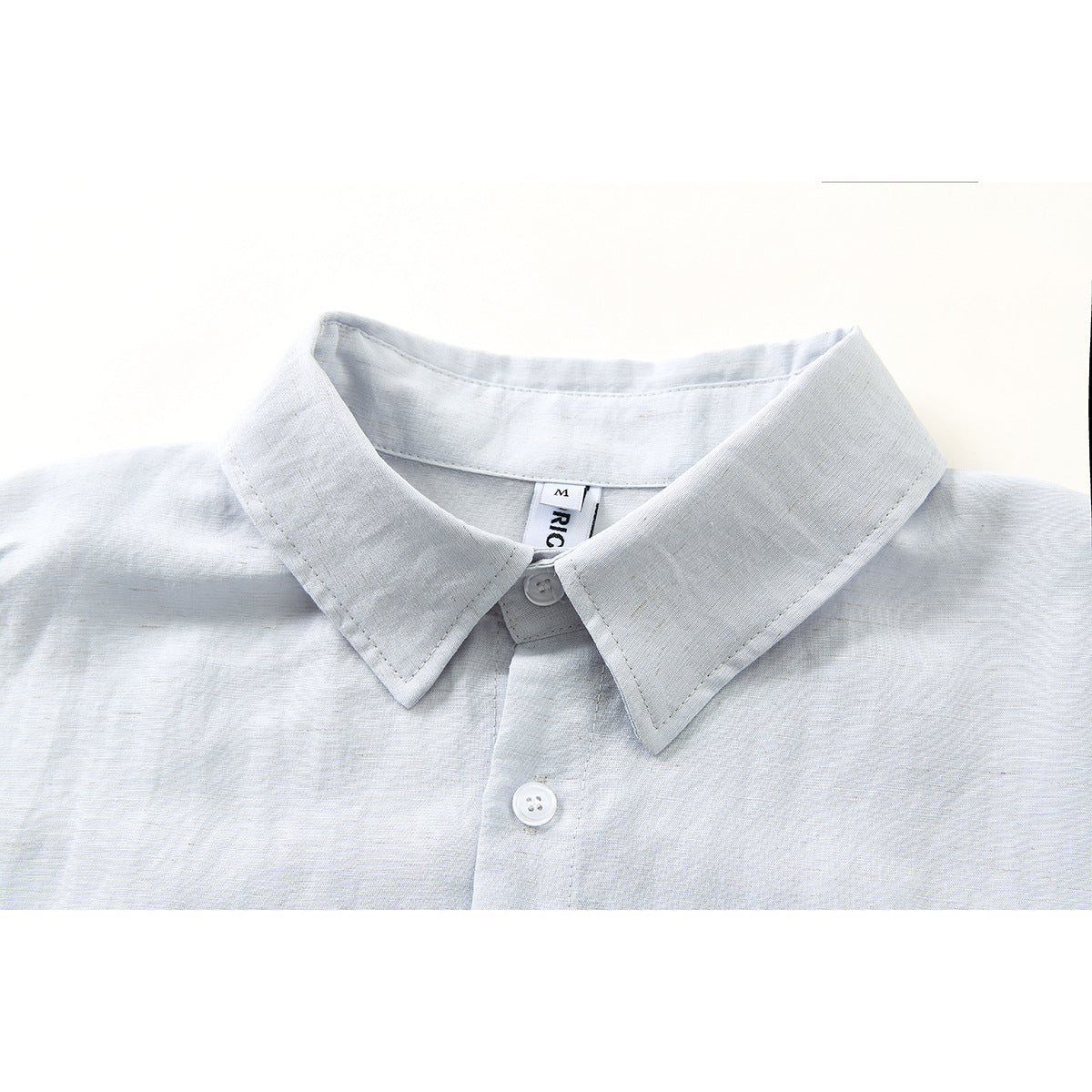 Close-up of a pale blue-gray button-down shirt collar, top button, and placket.