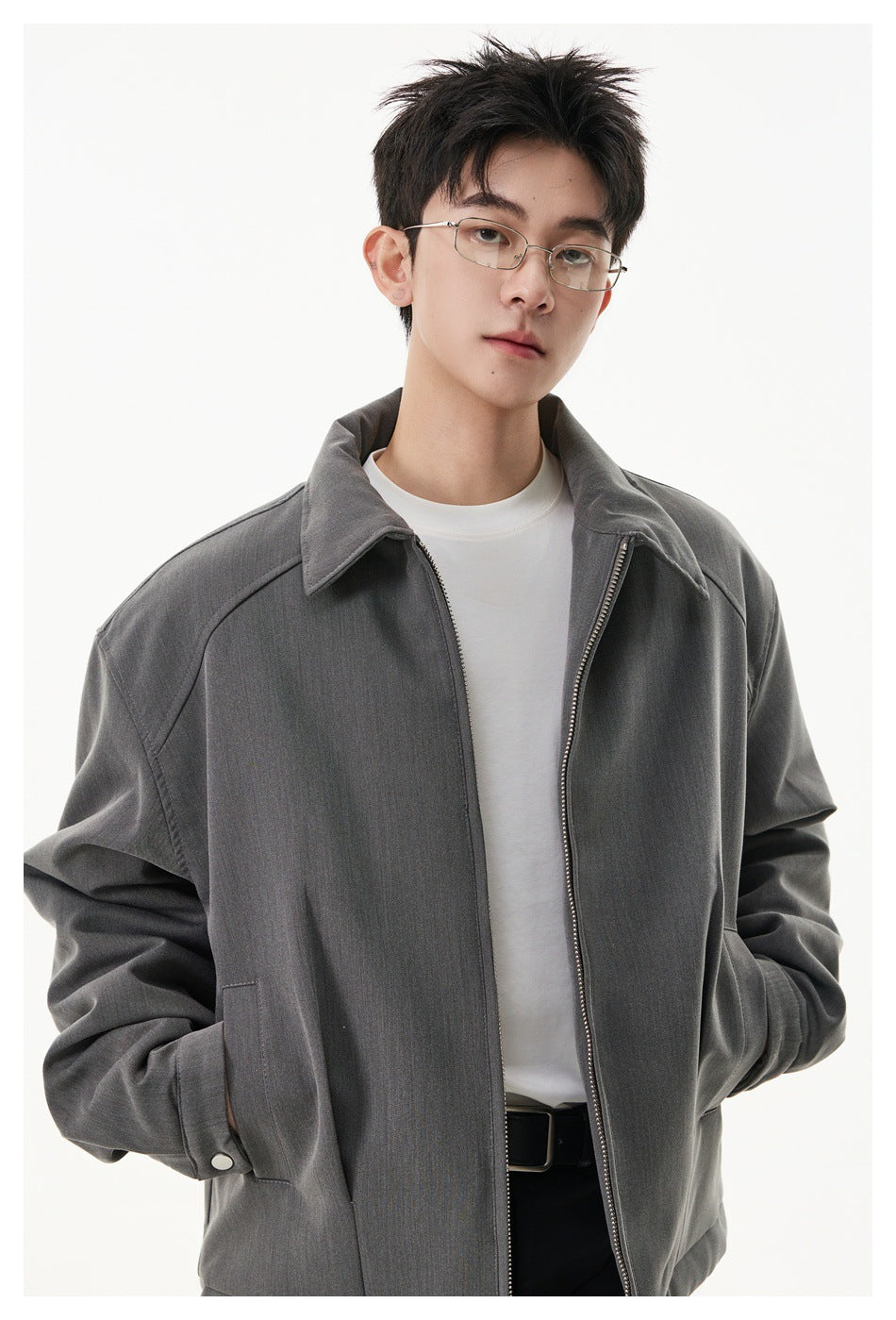 Close view of a model wearing an open charcoal gray jacket with a pointed collar and zip front.