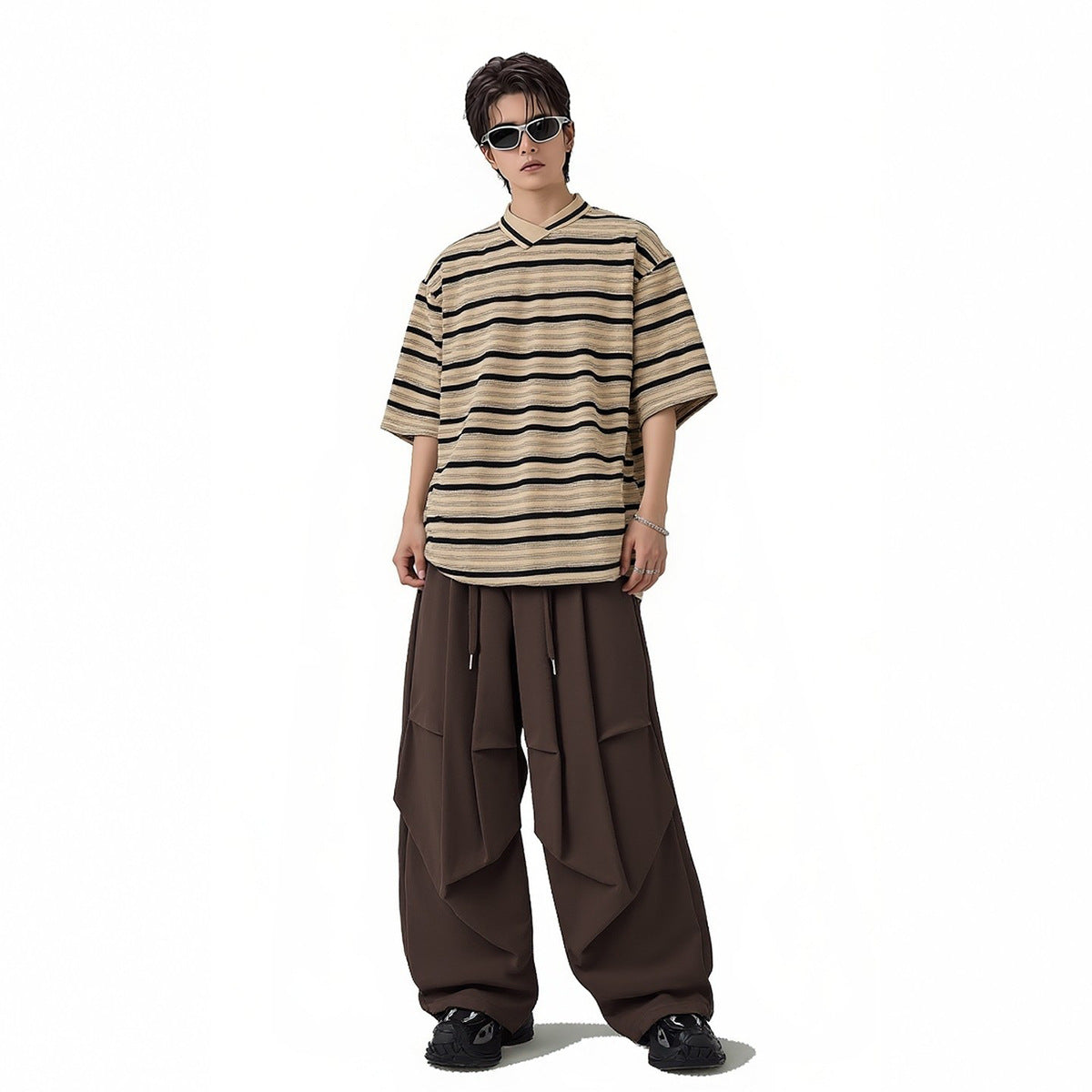 Model wearing an oversized beige-and-black striped V-neck shirt and wide dark brown trousers.