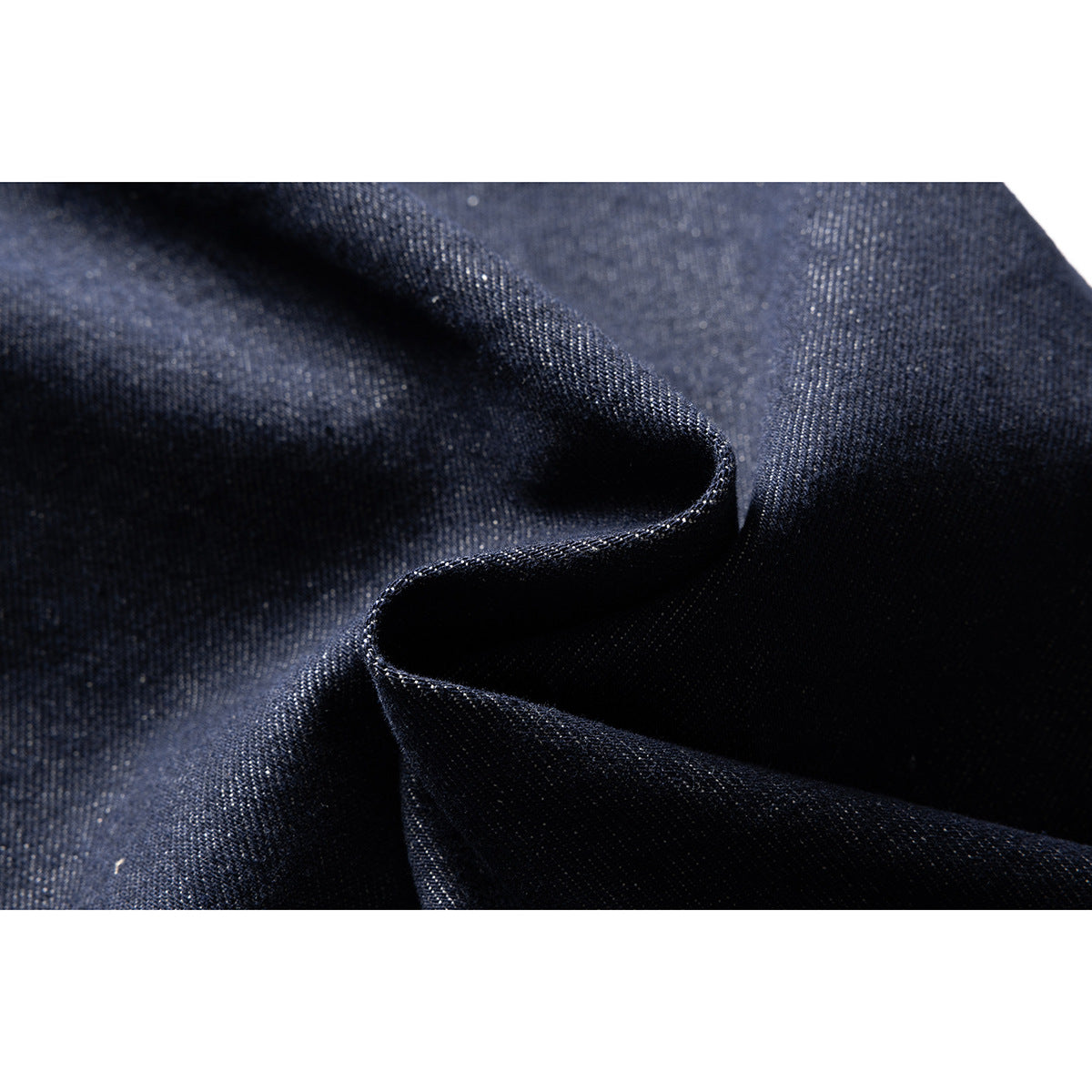 Close-up of dark indigo denim fabric folded to show its surface and texture.