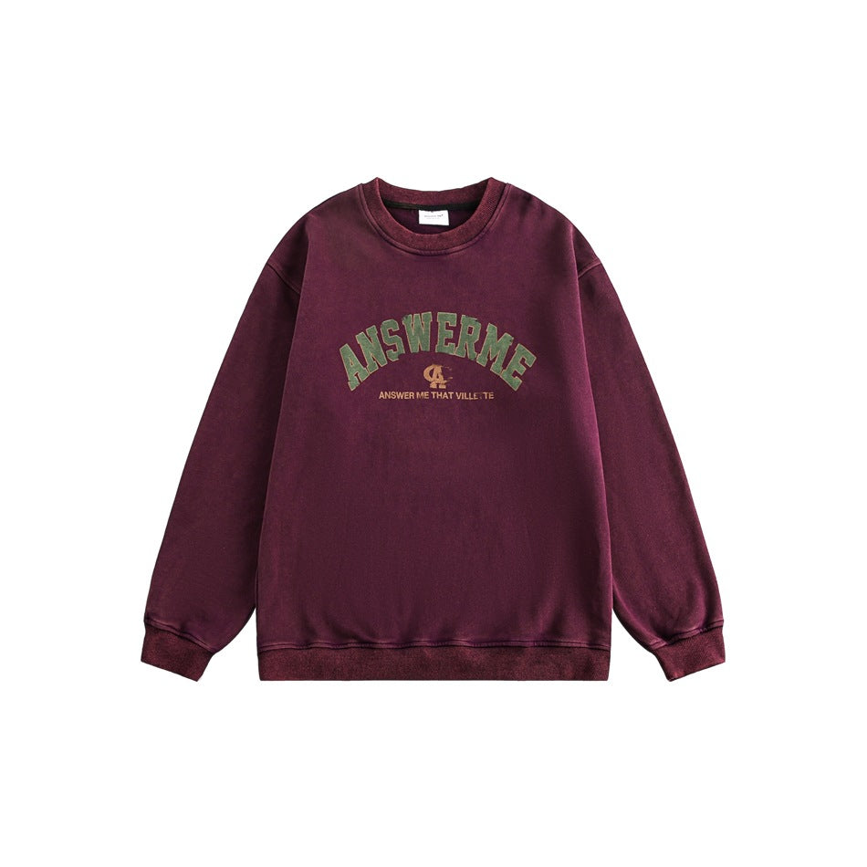 Purple burgundy washed crewneck sweatshirt flat lay with arched green ANSWERME chest graphic and ribbed trim