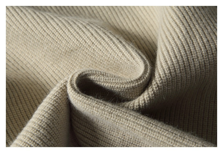 Close-up of beige rib-knit fabric draped in folds, showing its textured knit.