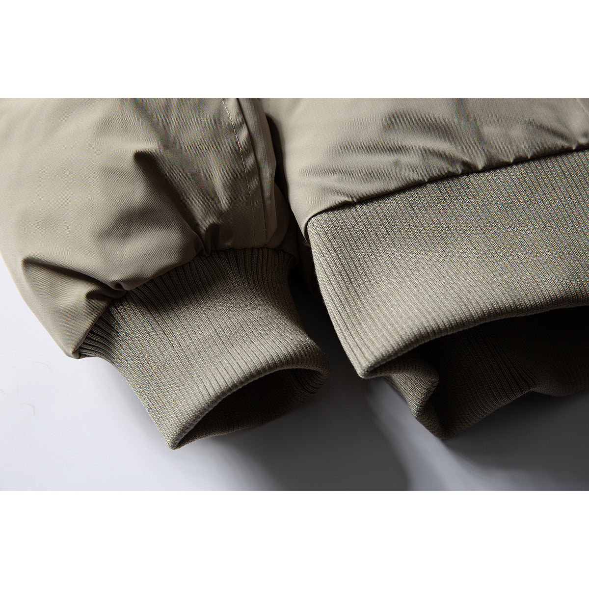 Close-up of a taupe jacket's ribbed knit cuffs and stitched sleeve seams.