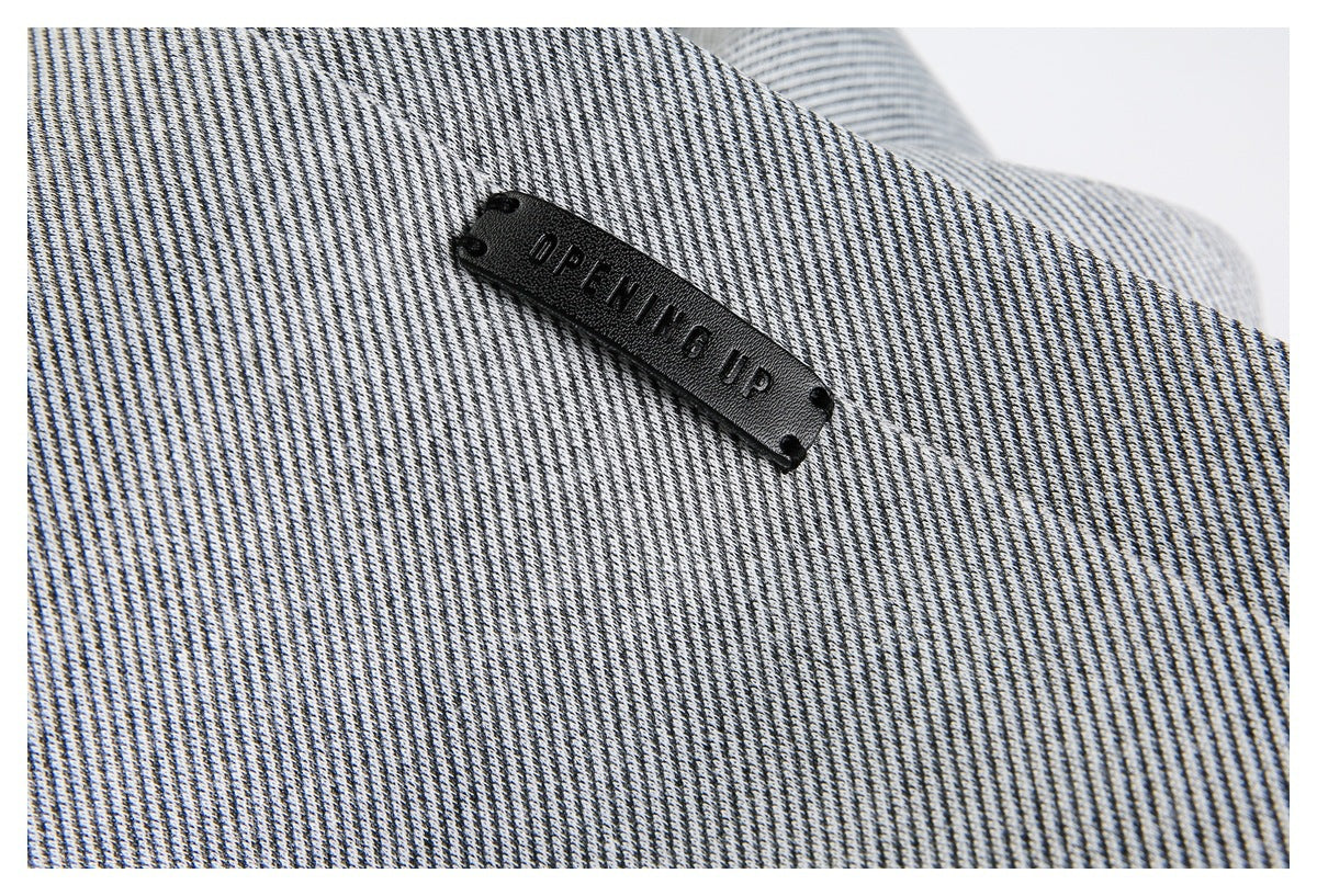Close-up of a black sewn label on gray-and-white striped jacket fabric.