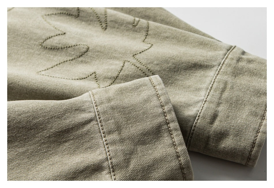 Close-up of a khaki-olive sleeve cuff beside leaf stitching on the garment.