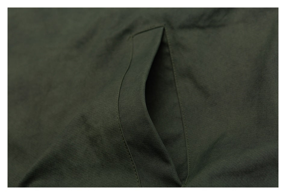 Close-up of a dark olive garment with a narrow folded opening and visible stitching.