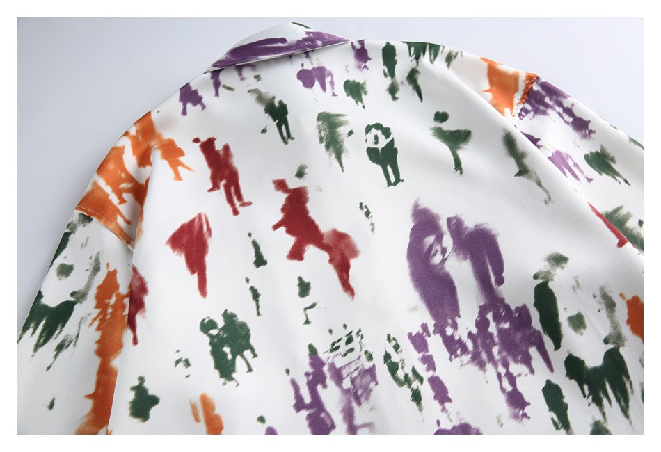 Close-up of the upper back and collar of a cream shirt with an abstract multicolored figure print.