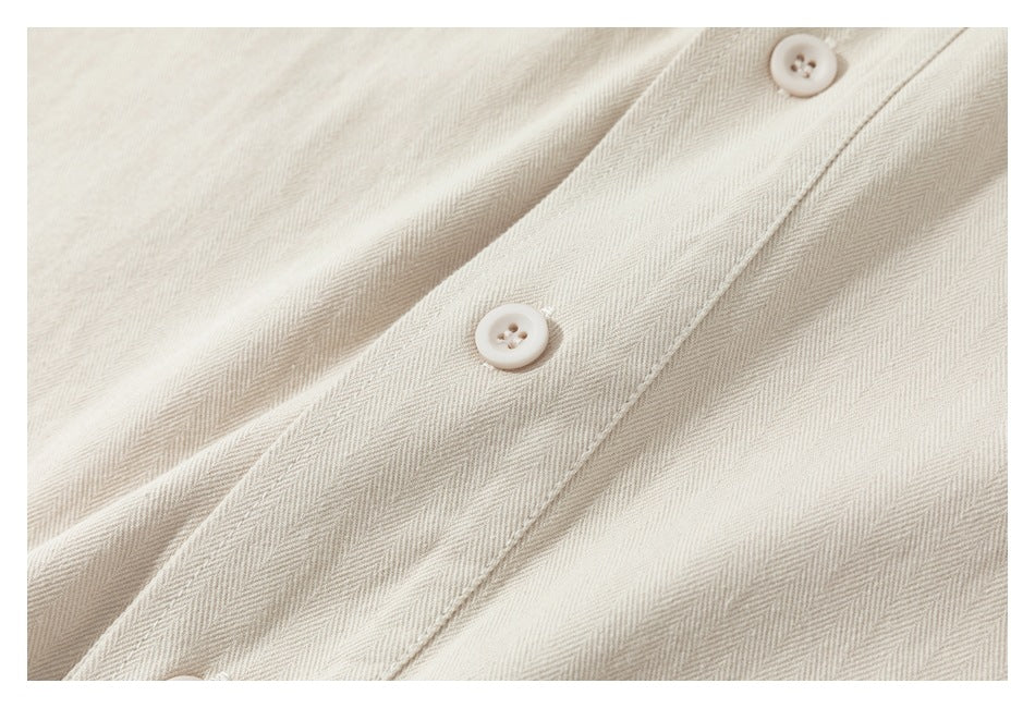 Close-up of two off-white buttons on the placket of a cream shirt.