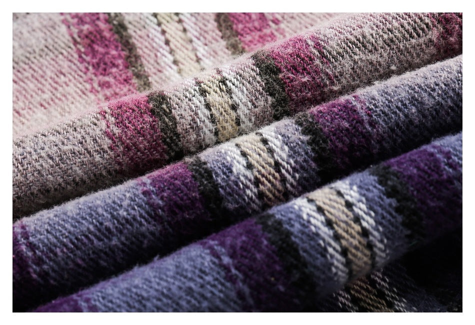 Macro view of the textured weave and pink, purple, gray, and cream plaid pattern of the fabric.
