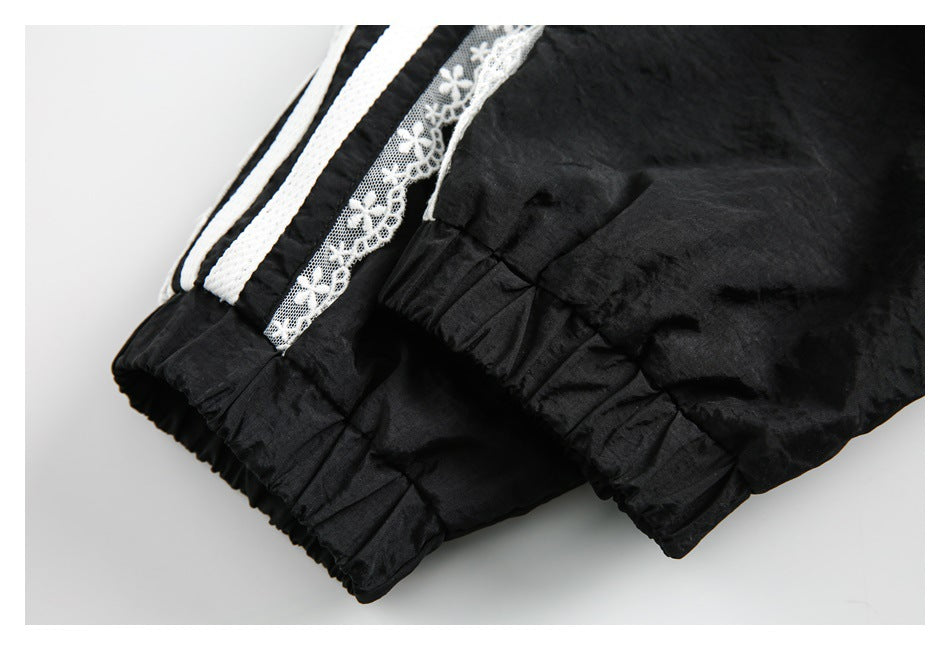 Close-up of black fabric with white lace and braided trim beside a gathered seam.