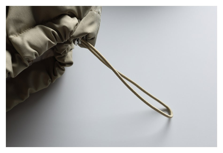 Close-up of the beige jacket’s gathered hem and long adjustment cord with a toggle.