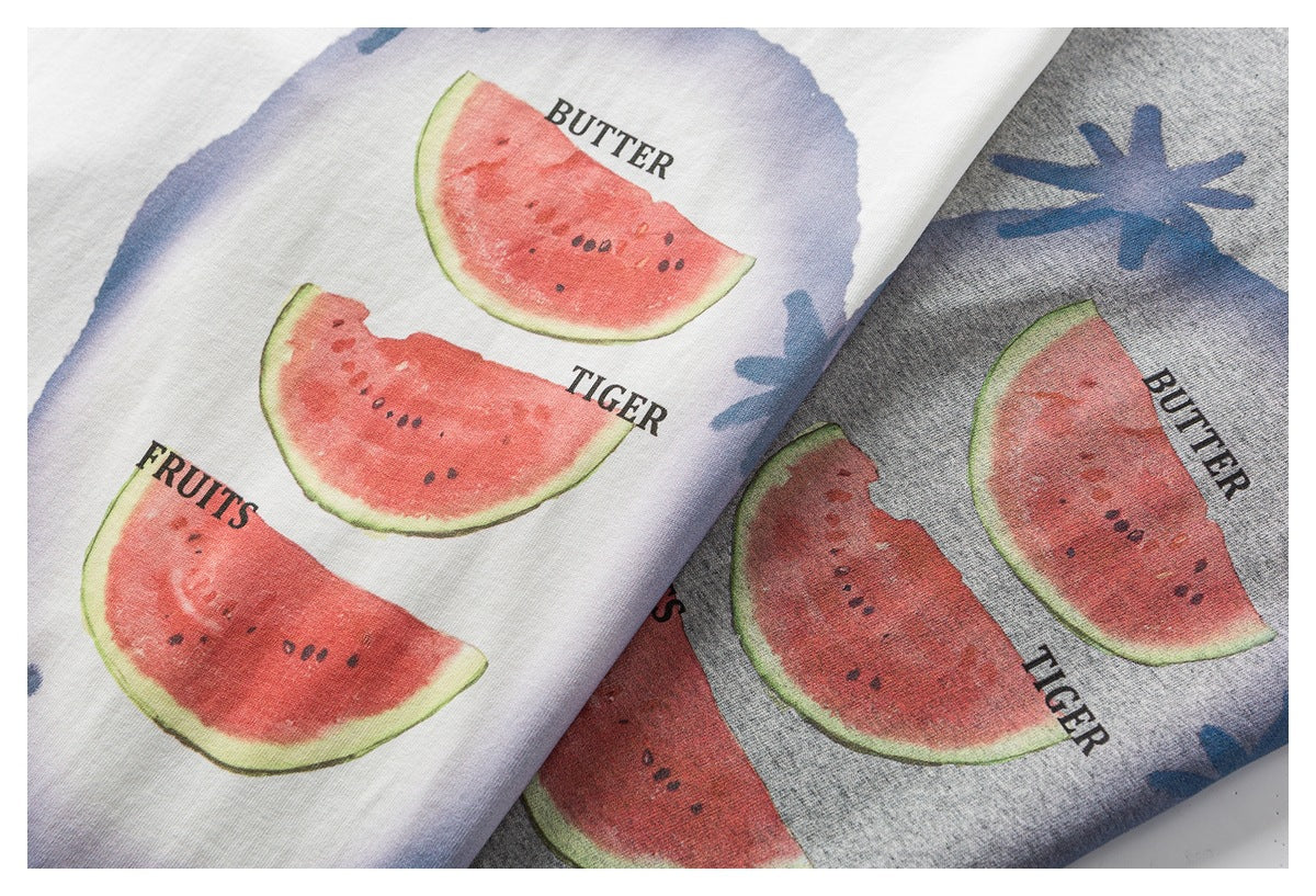 Close-up of white and heather-gray fabric showing watermelon slices, blue shapes, and English words.