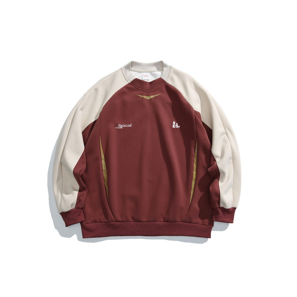 Brick red crewneck sweatshirt with cream raglan sleeves, ribbed trim and small chest embroidery, flat lay