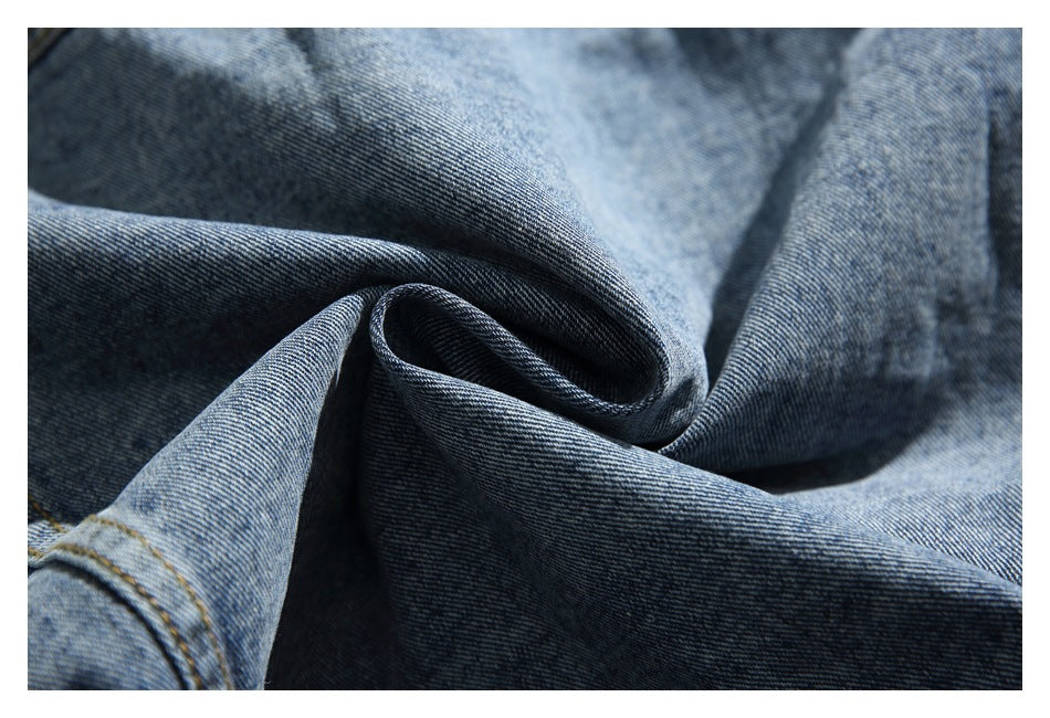Macro view of the blue denim fabric and diagonal twill weave, with a stitched seam at the edge.