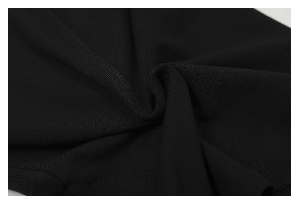 Close-up of black fabric gathered into folds, showing its fine texture and stitching.