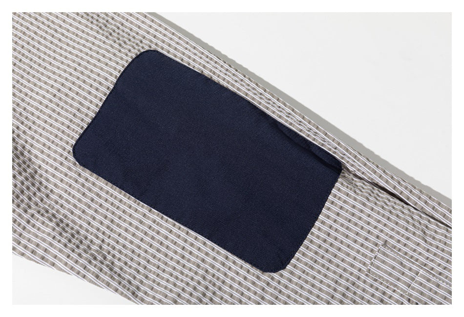 Close-up of a dark navy rectangular panel sewn onto taupe-and-white striped fabric.