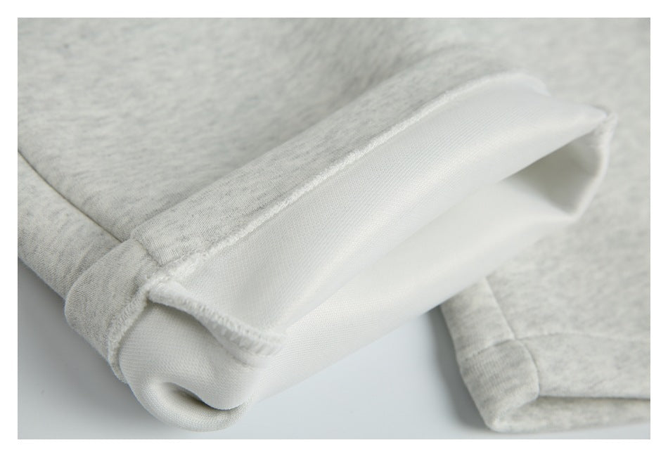 Inside close-up of a folded hem on light heather gray shorts, showing the pale inner fabric and stitching.