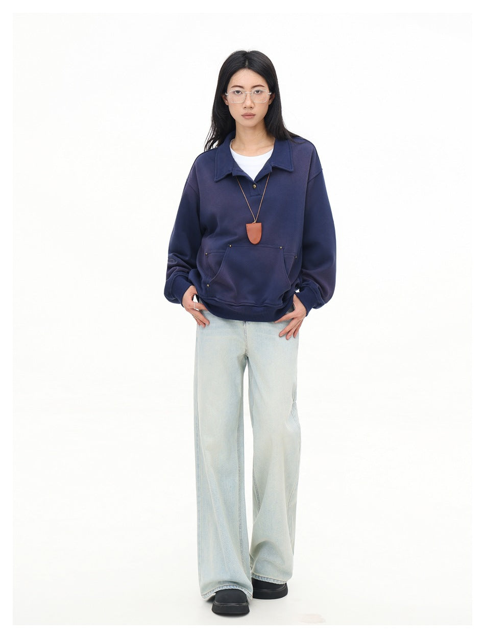 Full-length model wearing an oversized navy collared pullover with a pouch pocket and pale wide-leg jeans.