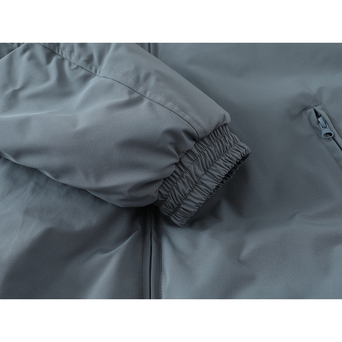 Close-up of the jacket's gathered elastic cuff, sleeve seam, and zip pocket.