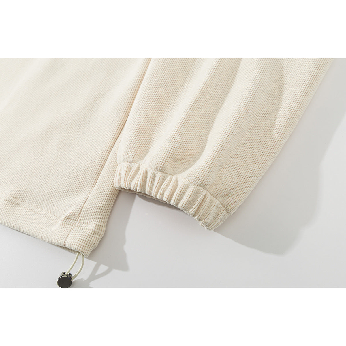 Close-up of an ivory ribbed jacket's elastic cuff and adjustable drawcord hem.