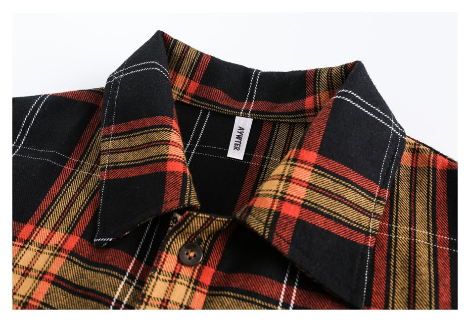 Close-up of the plaid shirt's pointed collar, top button, inner label, and red, mustard, black, and white checks.