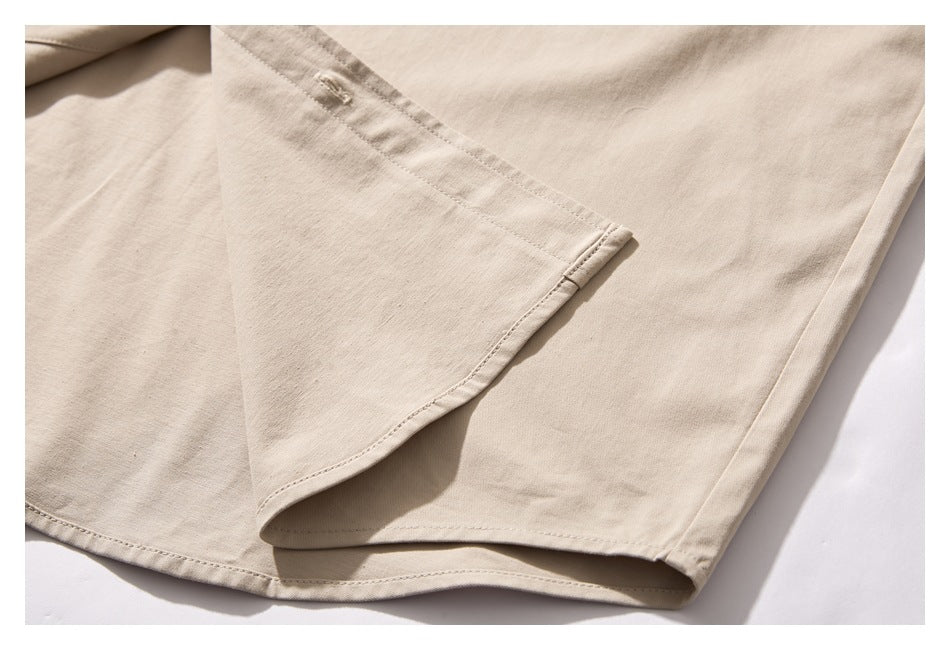 Close-up of a light beige garment showing overlapping panels, stitched seams, and a folded hem.
