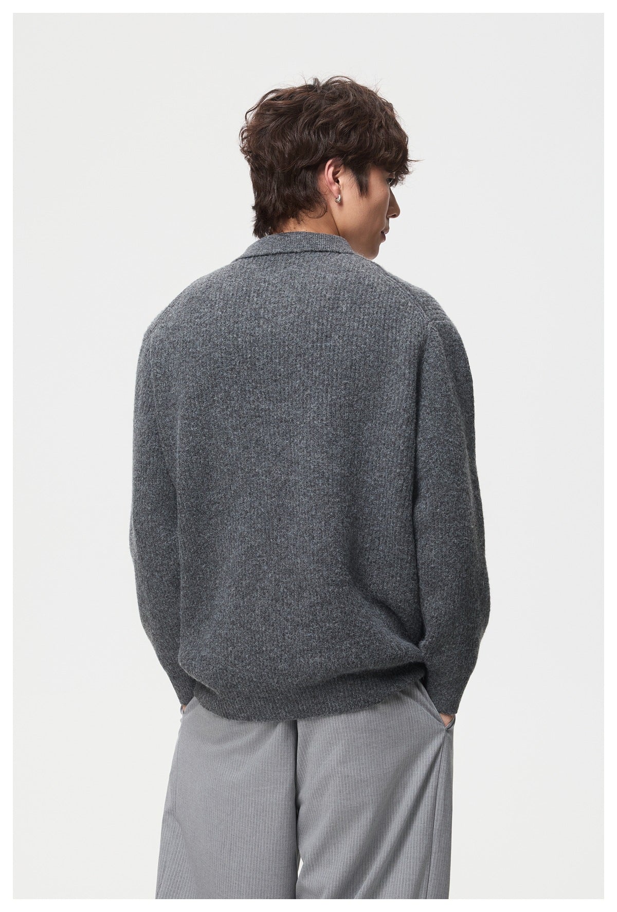 Back view of a model wearing a charcoal gray knit polo with a folded collar and ribbed hem.