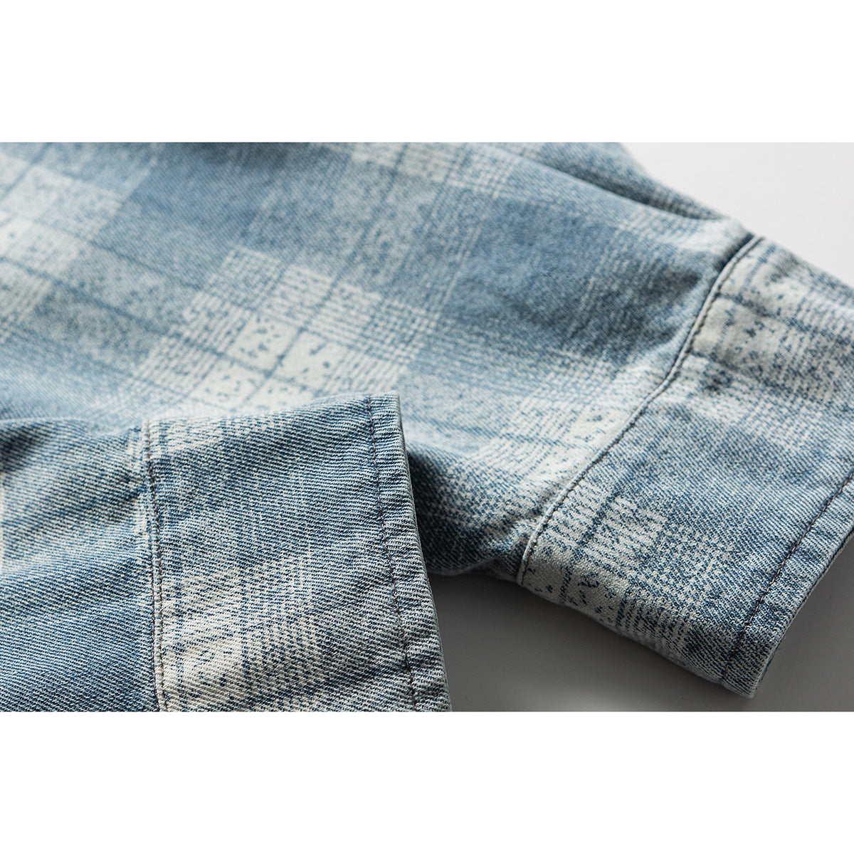 Close-up of a blue-gray patterned denim sleeve and cuff with visible seams.