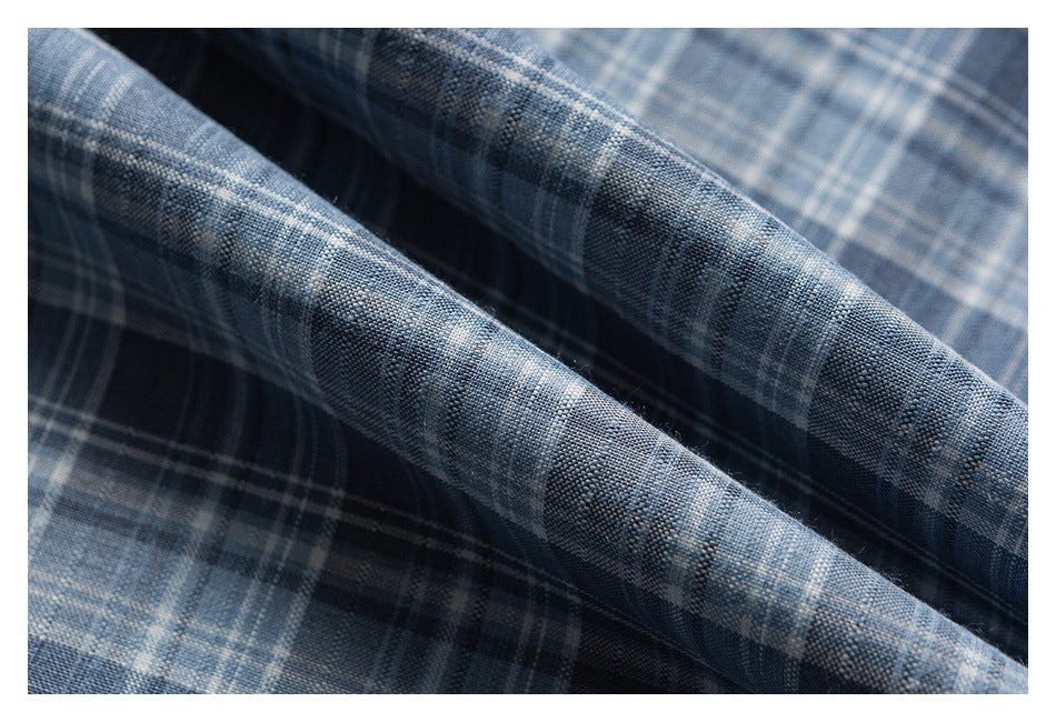 Folded blue-gray plaid fabric shown in close-up, revealing its woven texture.