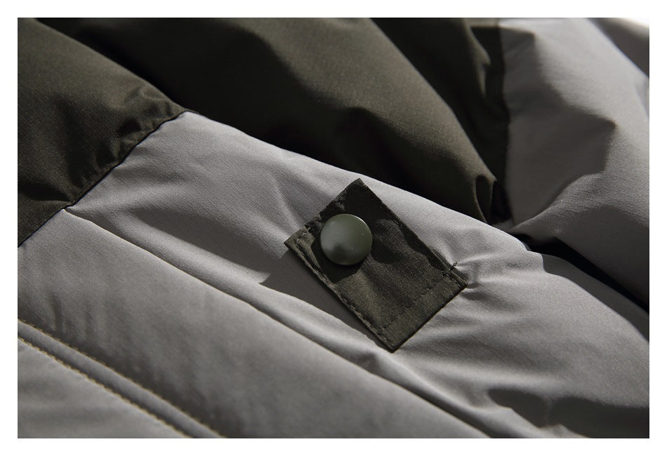 Close-up of a dark snap fastener on a gray jacket panel beside dark fabric.