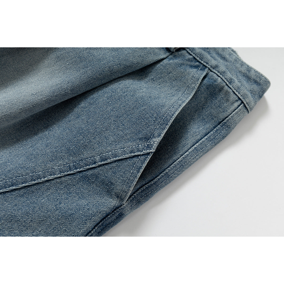 Close-up of blue denim fabric and intersecting stitched seams.