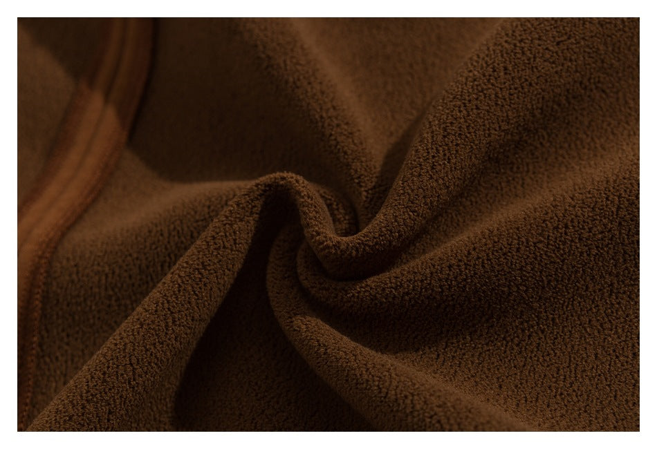 Close-up of dark brown plush-textured fabric in folds, with a stitched edge visible at left.