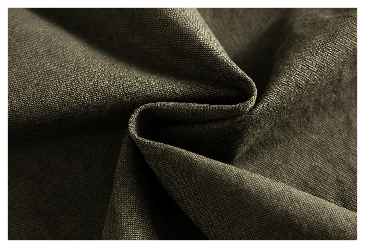 Extreme close-up of dark olive fabric gathered into folds, highlighting its fine woven texture.