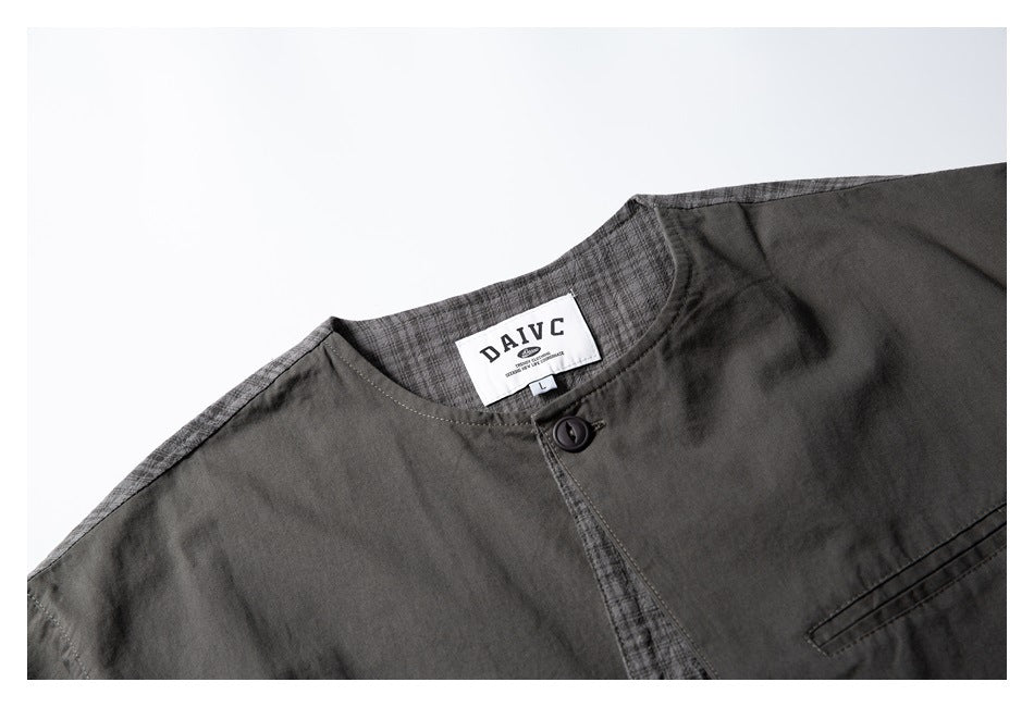 Close-up of a charcoal shirt collar, button, checked placket, and sewn neck label.