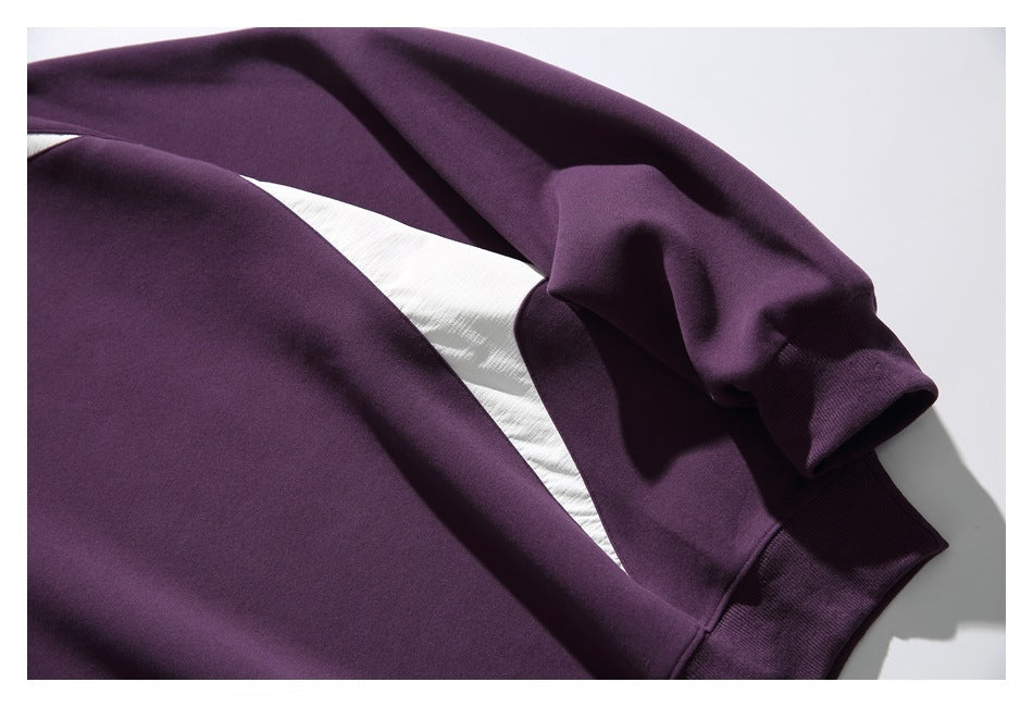 Close-up of the plum sweatshirt's sleeve, ribbed cuff, and contrasting white side panel.