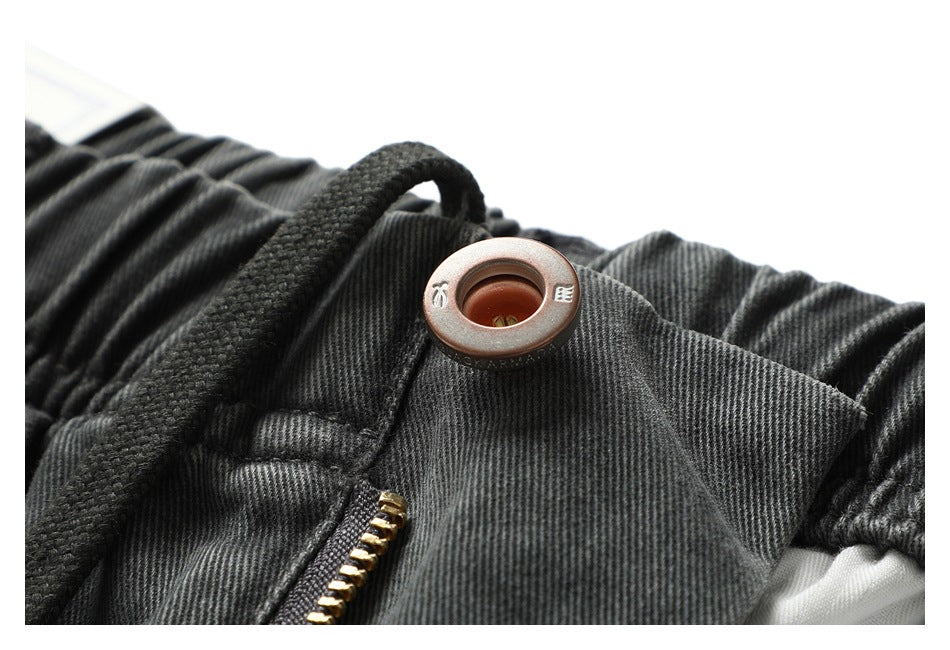Close-up of charcoal shorts showing a drawstring, metal eyelet and gold-tone zipper.
