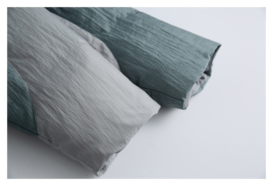 Close-up of pale gray and teal garment sleeves folded against a light background.