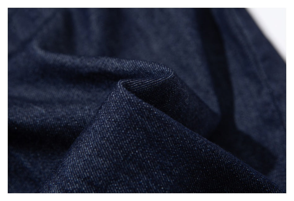Macro view of dark indigo denim fabric folded to show its woven texture.