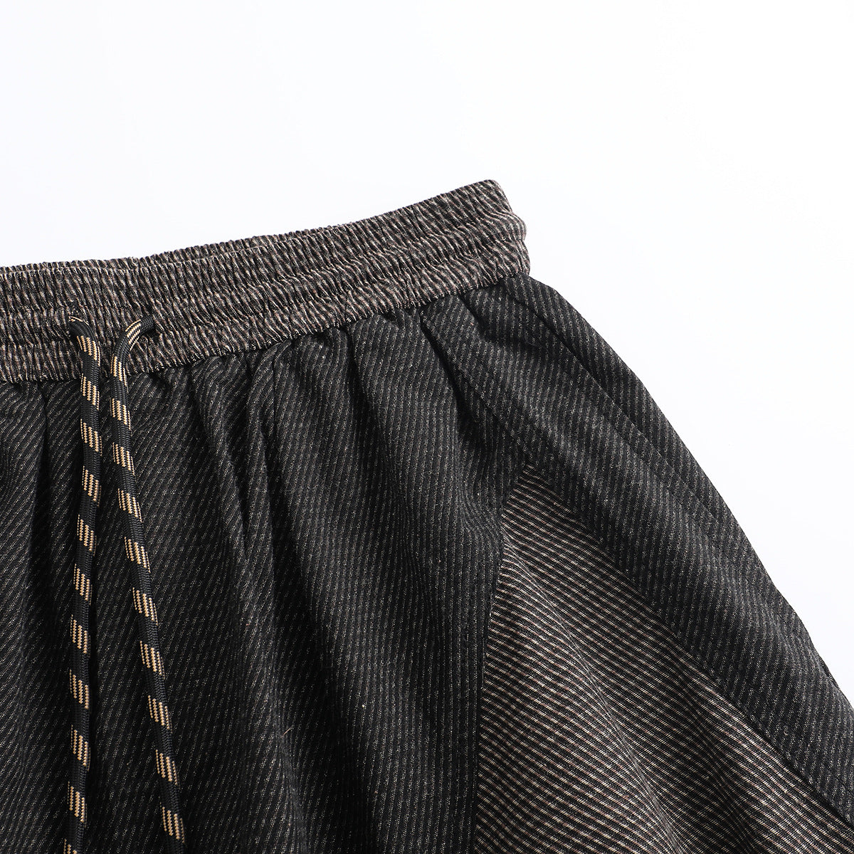 Close-up of dark striped pants showing the elastic waistband, drawstring, and angled pocket opening.