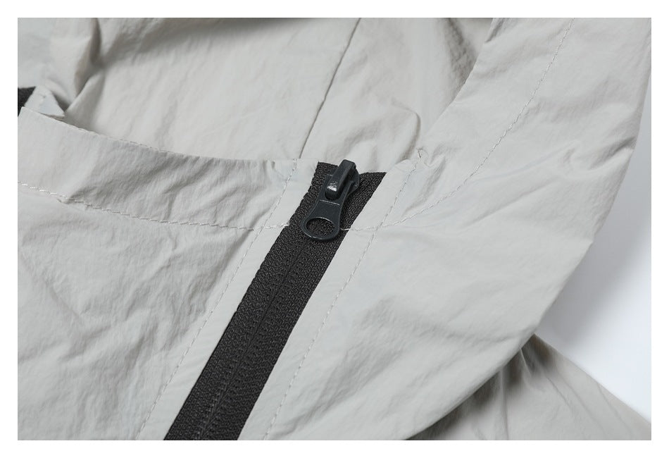 Close-up of a black zipper and stitching on light gray jacket fabric.