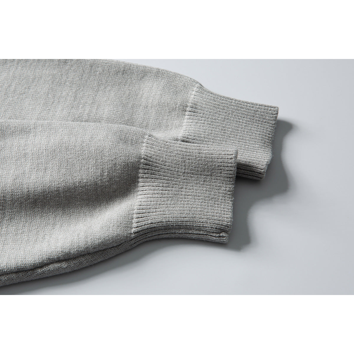 Close-up of a light gray sweater's long sleeve and wide ribbed cuff.