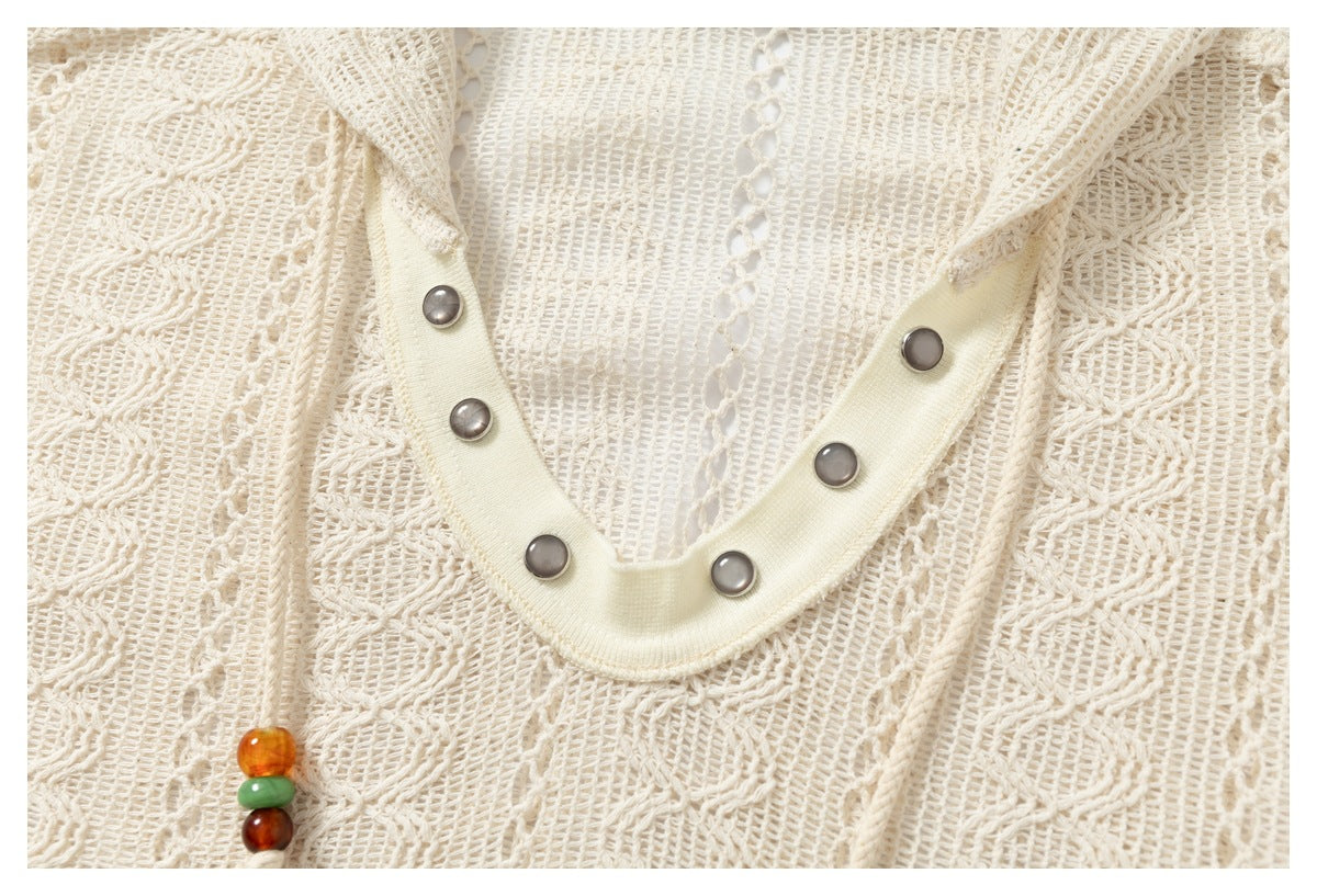 Close-up of the cream open-knit pullover’s V-neck snap trim and beaded drawstring ends.