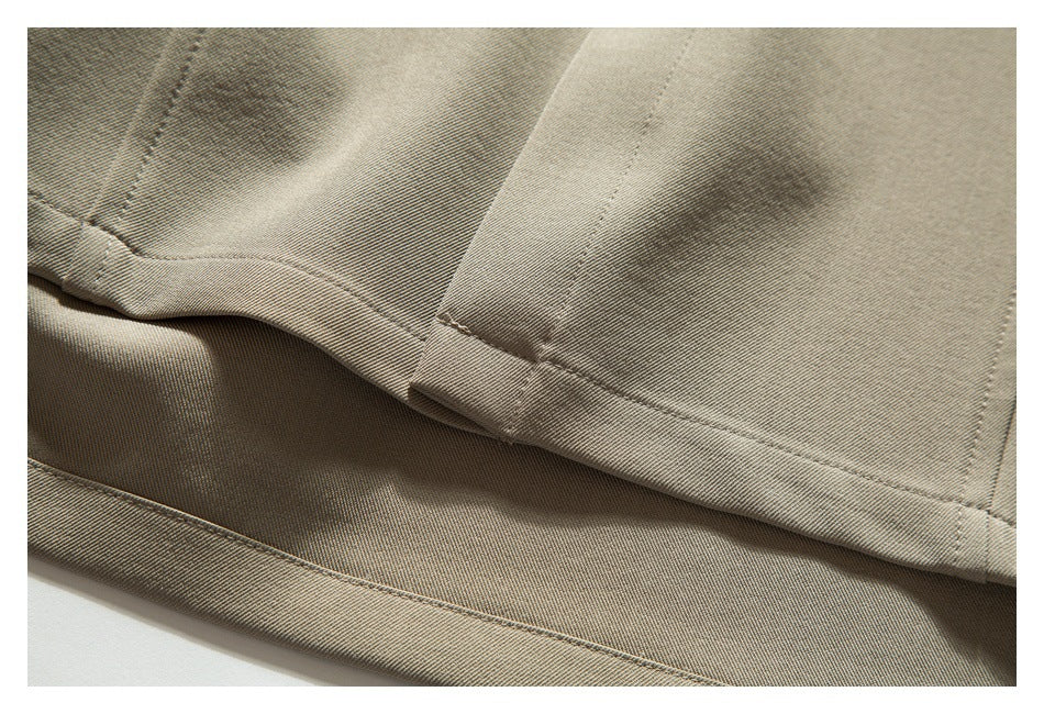 Close-up of overlapping beige garment panels with stitched hems and visible fabric texture.