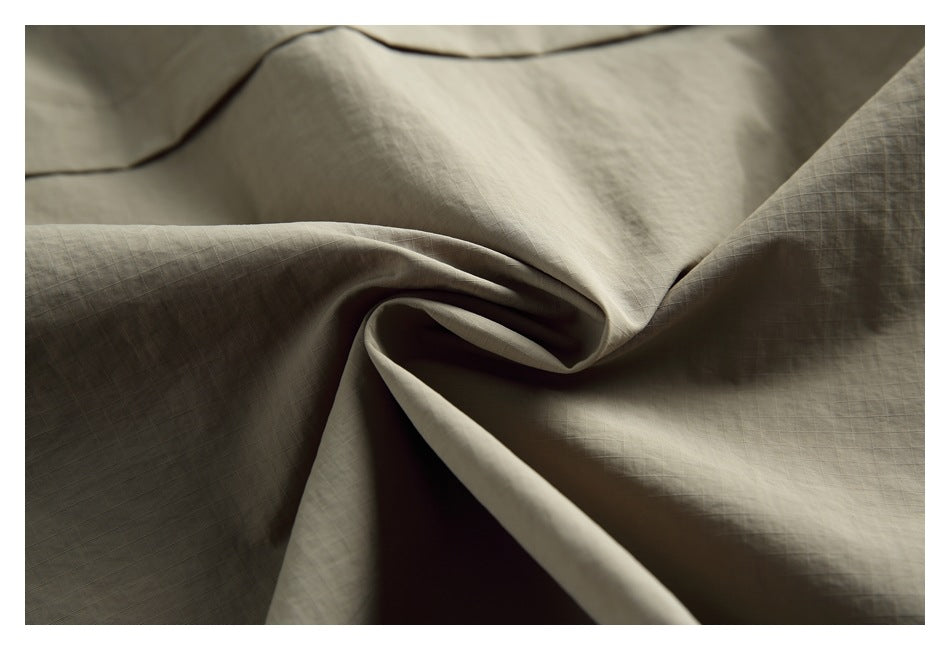 Close-up of the khaki jacket fabric gathered into folds, revealing a subtle grid texture.