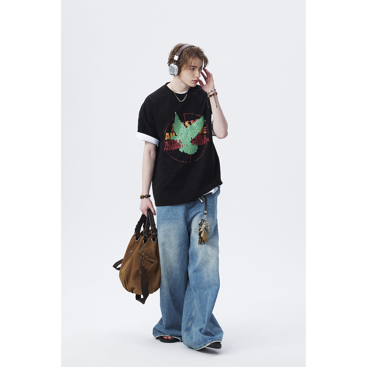 Model wearing an oversized black T-shirt with a green eagle graphic and rolled white sleeve cuffs, paired with wide