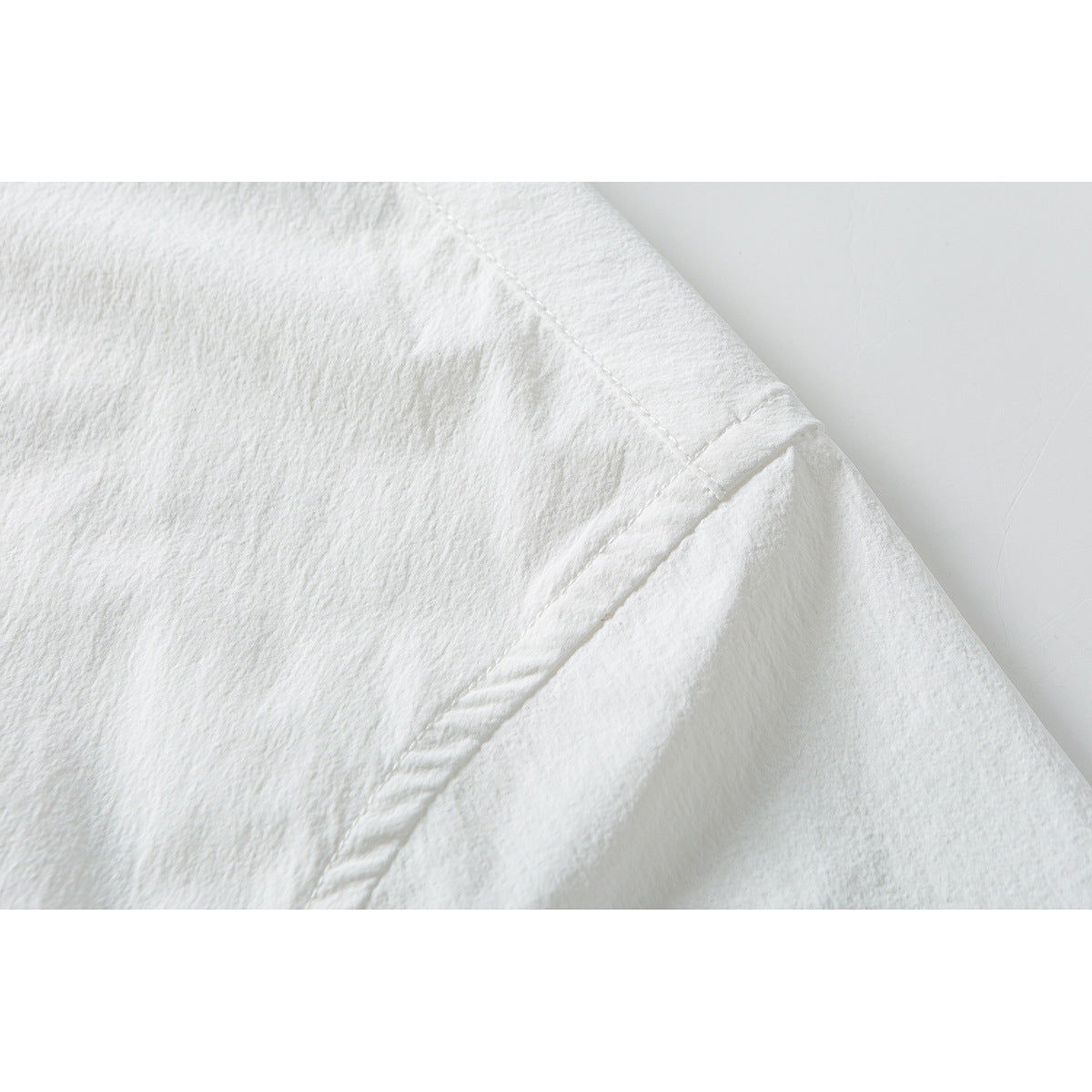 Close-up of white shirt fabric showing a curved stitched seam and folded edge.