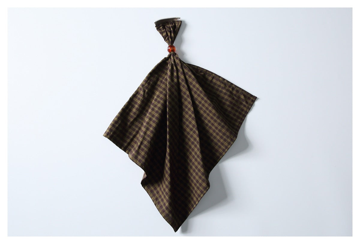 Brown and olive plaid fabric gathered with a red bead, shown against a plain white background.