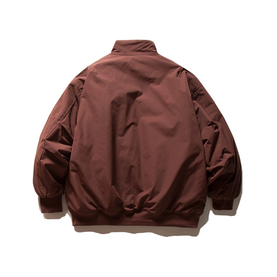 Back view of a rust-brown jacket with a stand collar, gathered sleeves, ribbed cuffs, and hem.