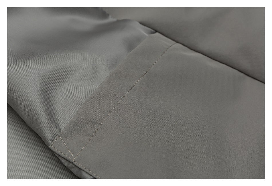 Close-up of a stitched seam on gray-olive fabric.