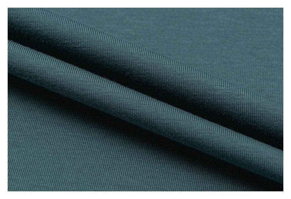 Close-up showing the fine knit texture of teal fabric folded into soft ridges.